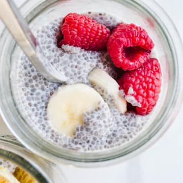 A jar filled with chia pudding and topped with fresh raspberries and bananas.