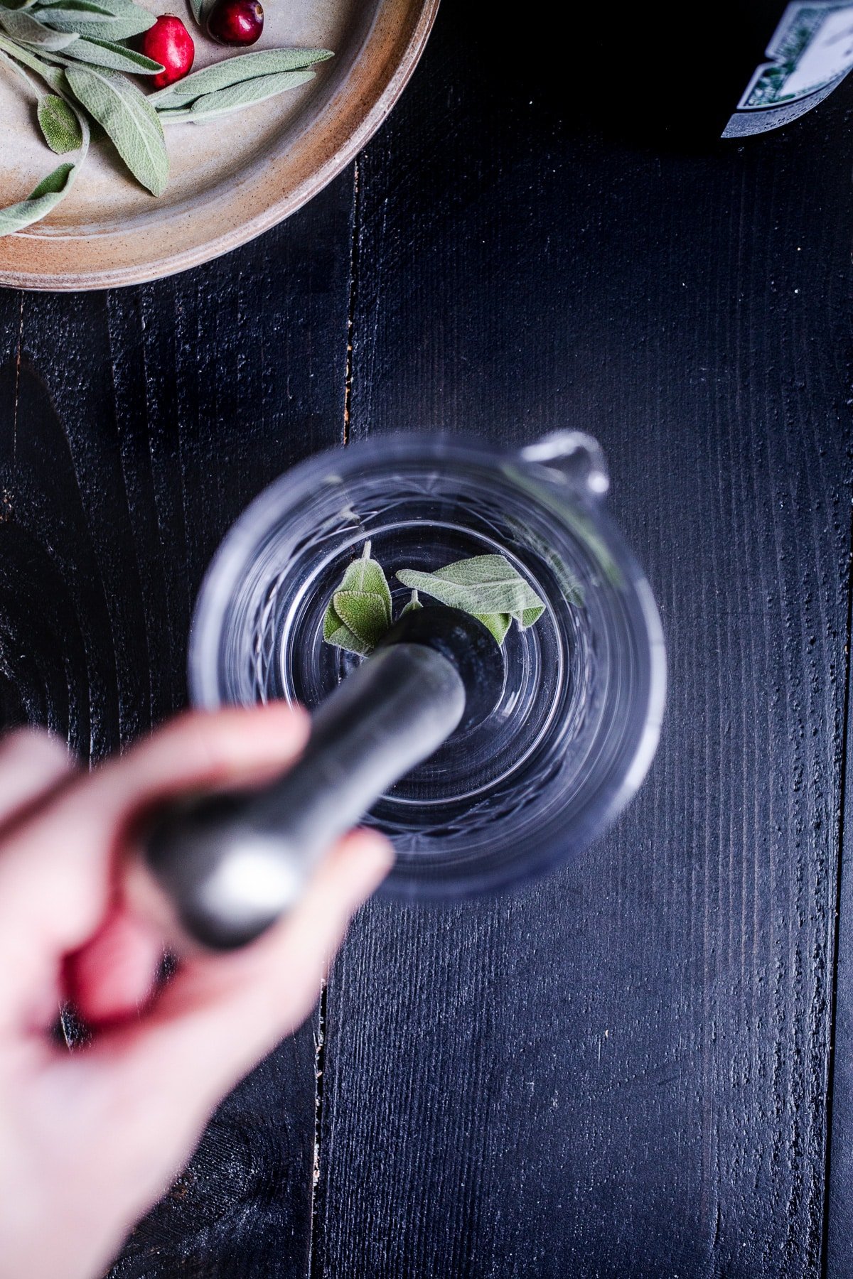 Sage being muddles in a glass.