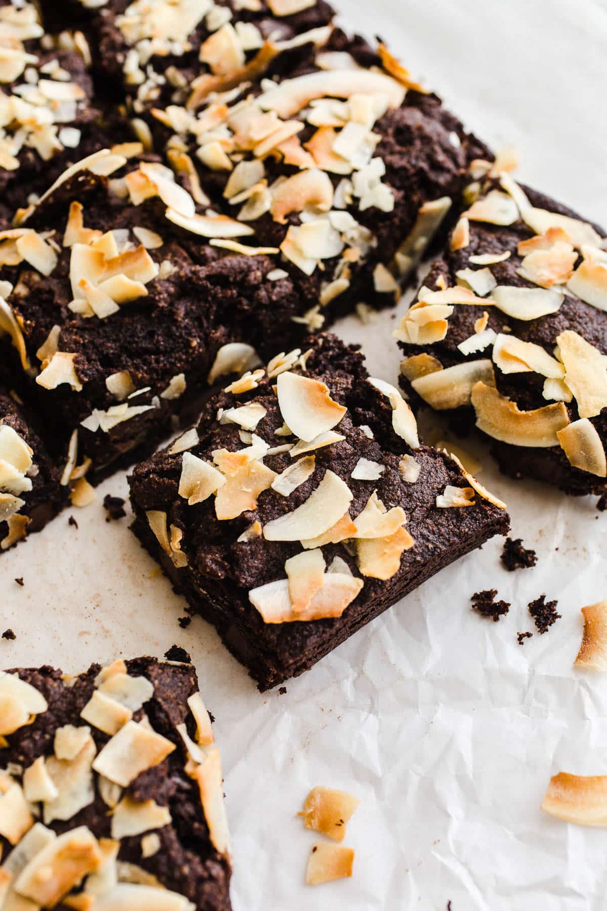 Chocolate coconut bars on white parchment paper. 