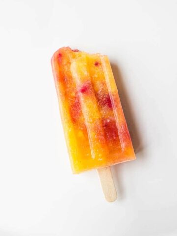 A mango popsicle on a white surface.