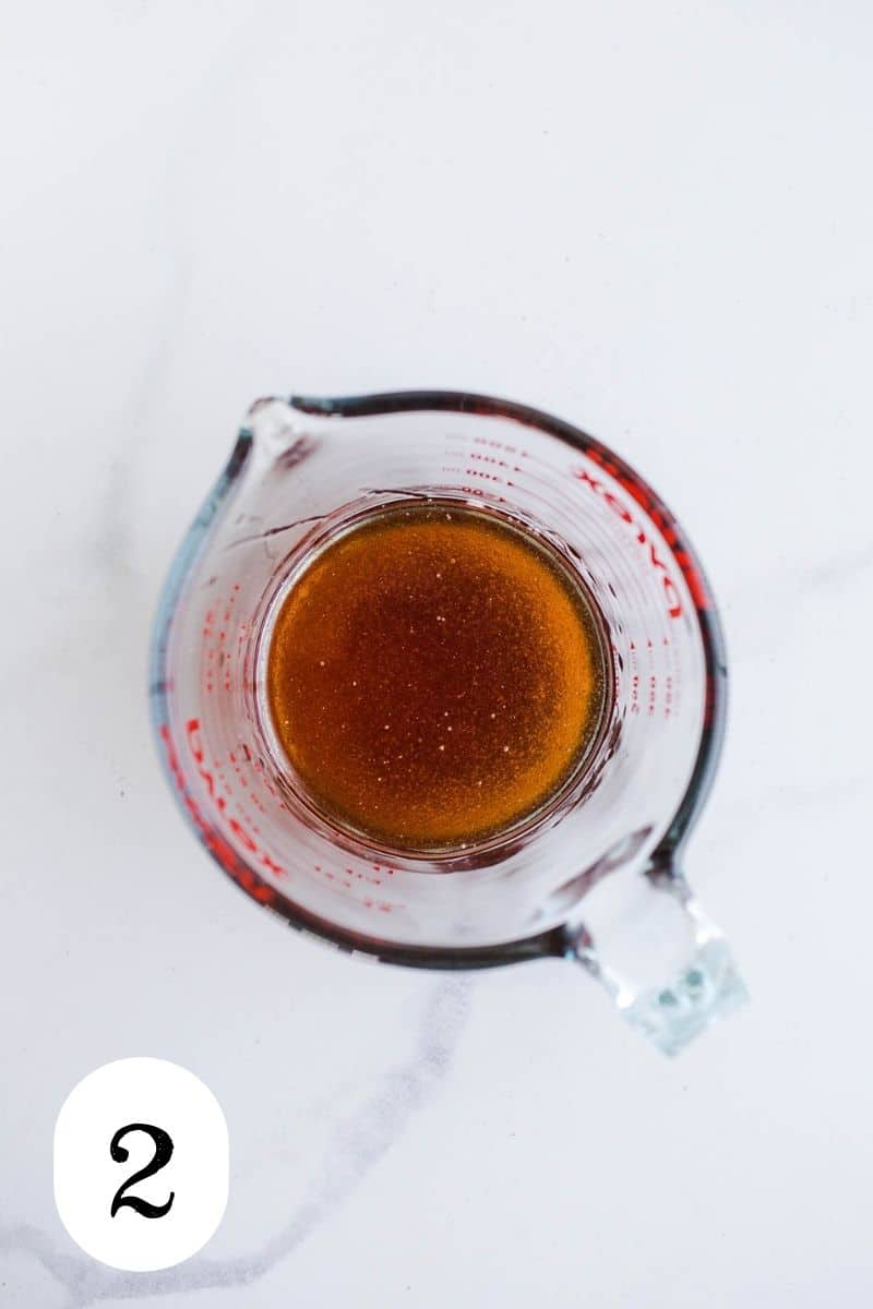 A glass measuring cup with maple syrup and coconut oil.