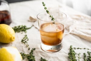An old fashioned in a glass with a sprig of thyme.
