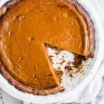 Carrot Pie in a white dish with a slice cut out of it.