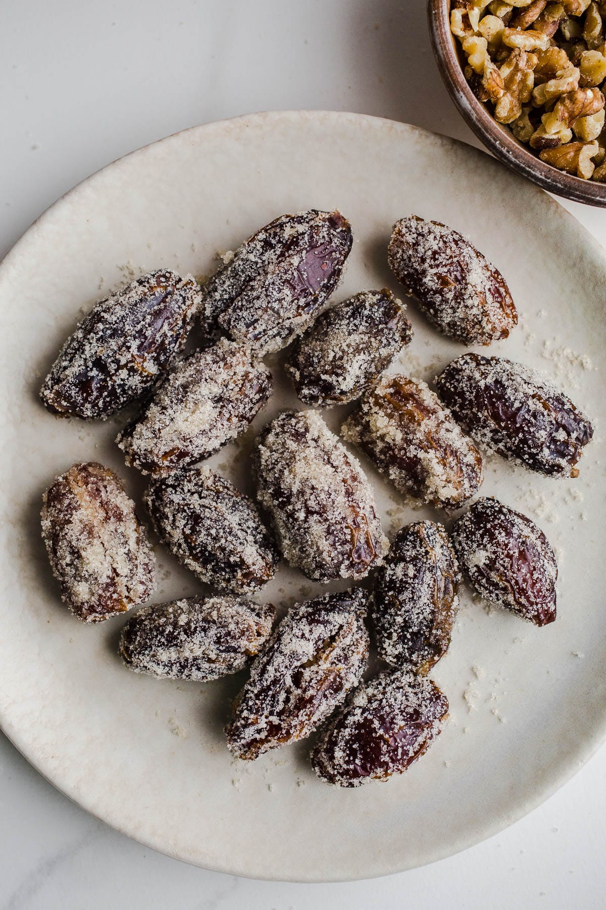 Sugared dates on a cream plate.