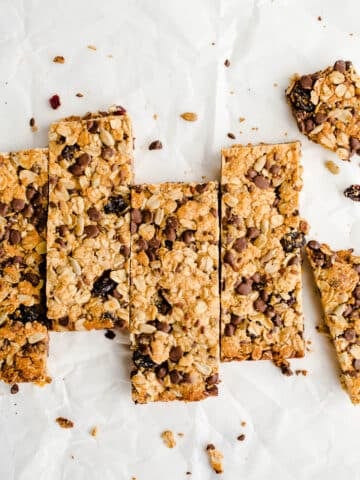 Granola bars lined up in a row on a piece of white parchment paper.