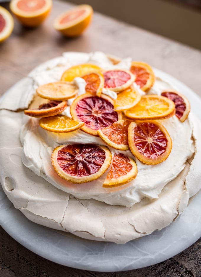 A pavlova topped with cream and citrus slices. 