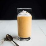 A persimmon smoothie with coconut whip on top.