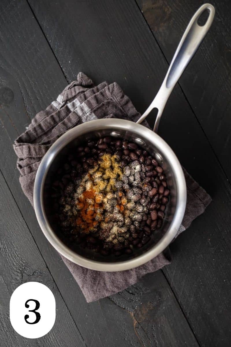 A saucepan with black beans and spices. 