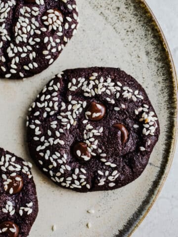 Chocolate cookies with sesame seeds on a plate.