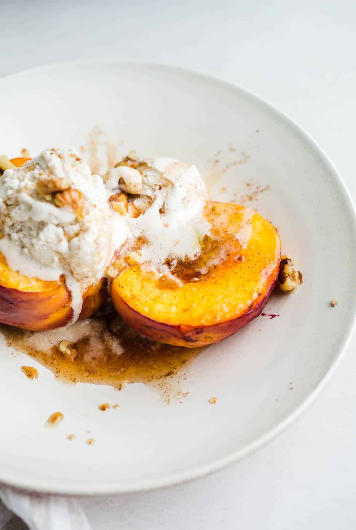 Baked peaches in a bowl with ice cream. 