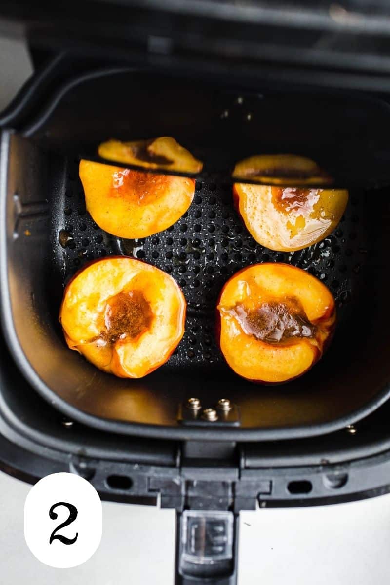 Basted peach halves in an air fryer.