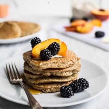 A stack of pancakes topped with fruit.