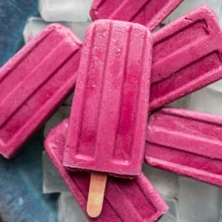 Strawberry-beet popsicles on a blue plate.