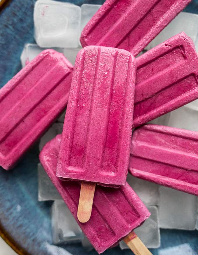 Bright pink strawberry popsicles on top of ice cubes.