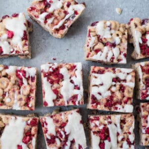 Raspberry coconut cereal treats on a blue surface.