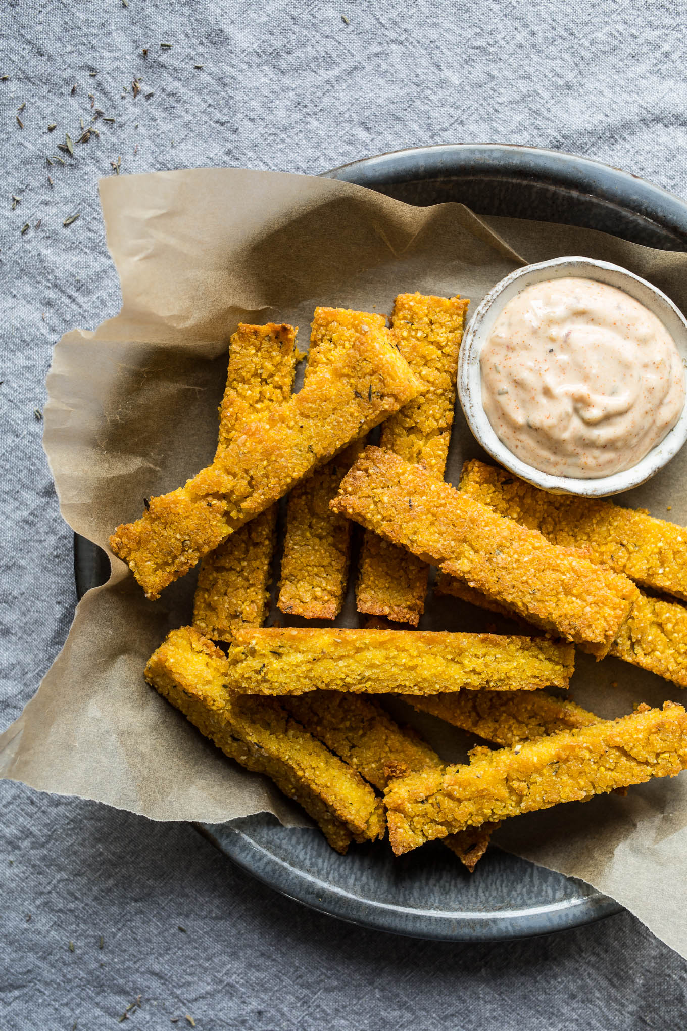 Crispy polenta fries in a blue dish on a blue tablecloth.