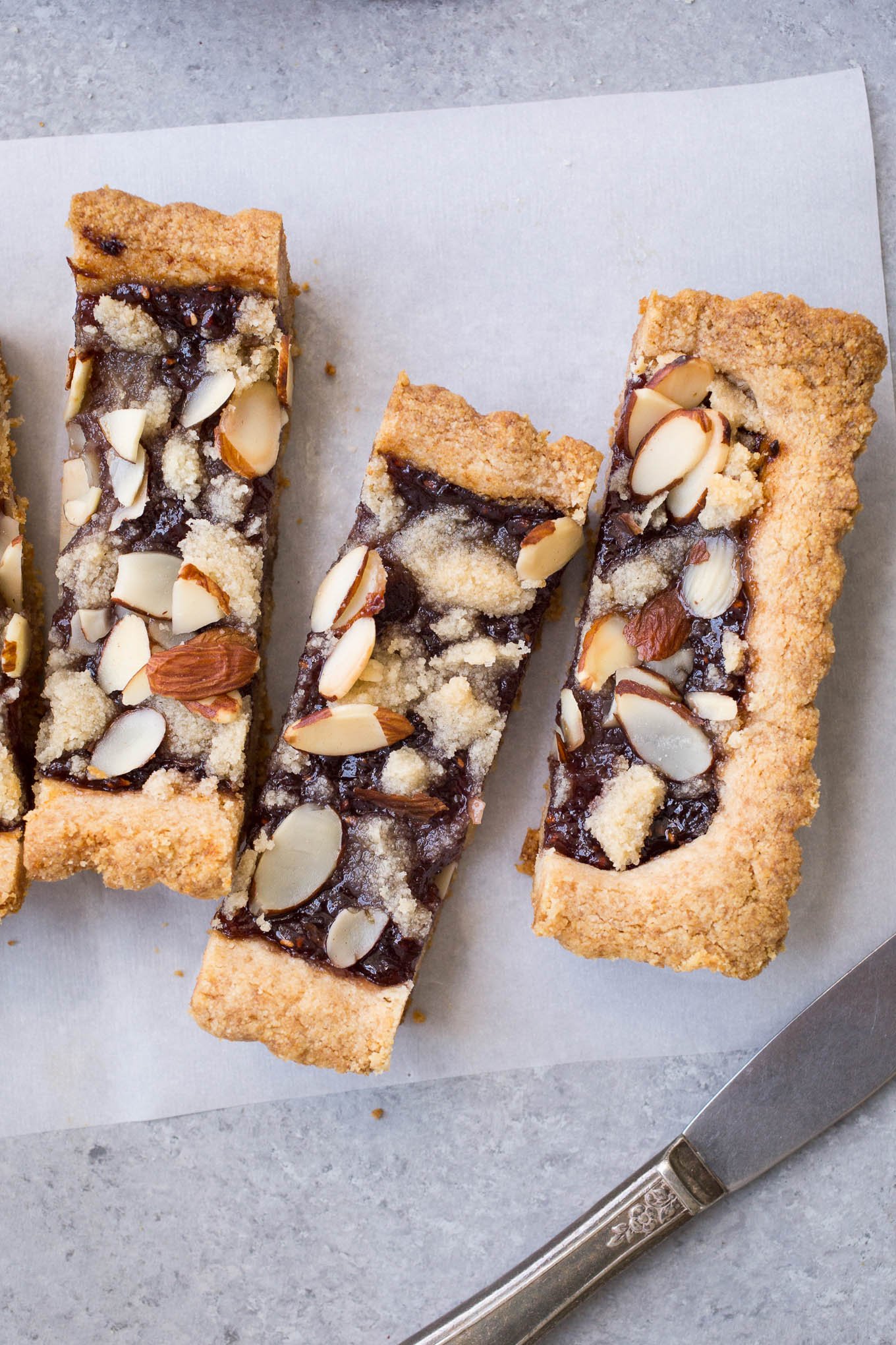 Slices of almond raspberry tart on parchment paper. 