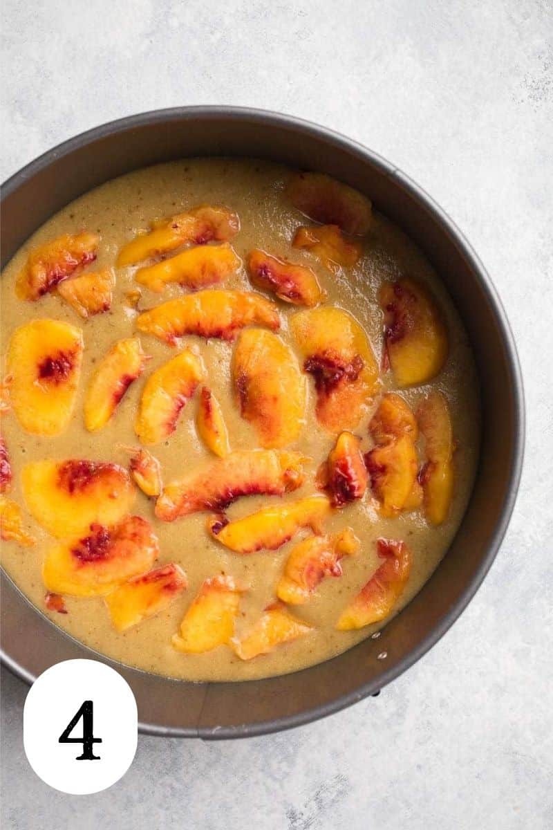 Peaches in cake batter in a round pan.