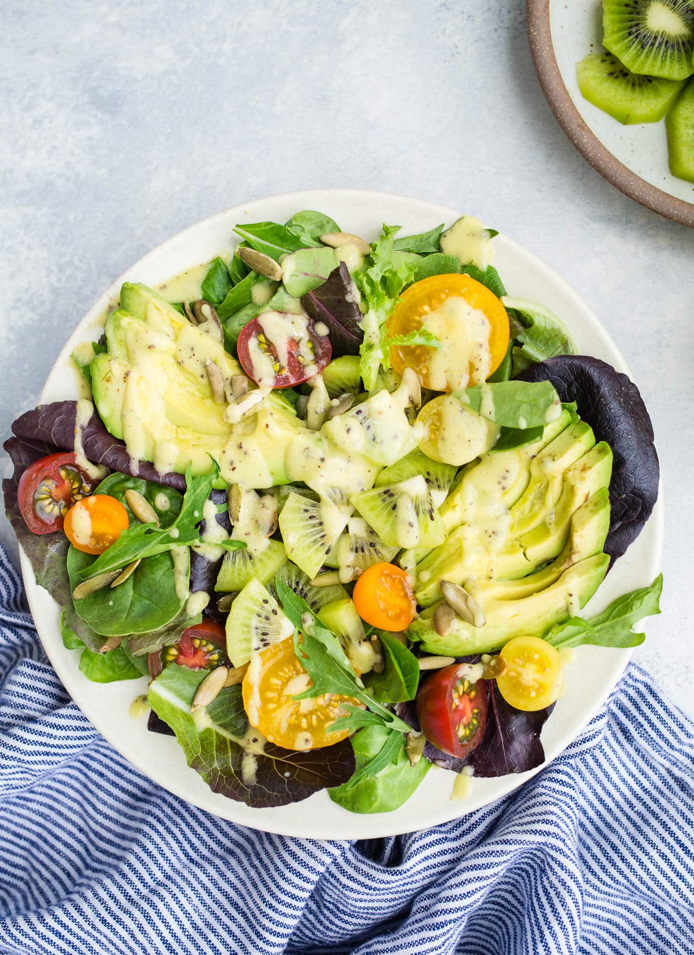 Salad with tomatoes and veggies on a white plate.