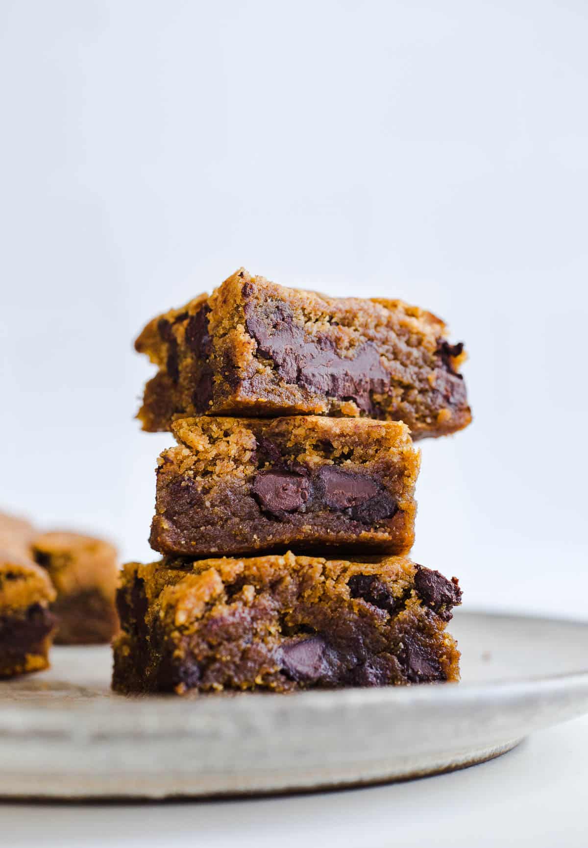 Chocolate chip blondies stacked on a plate.