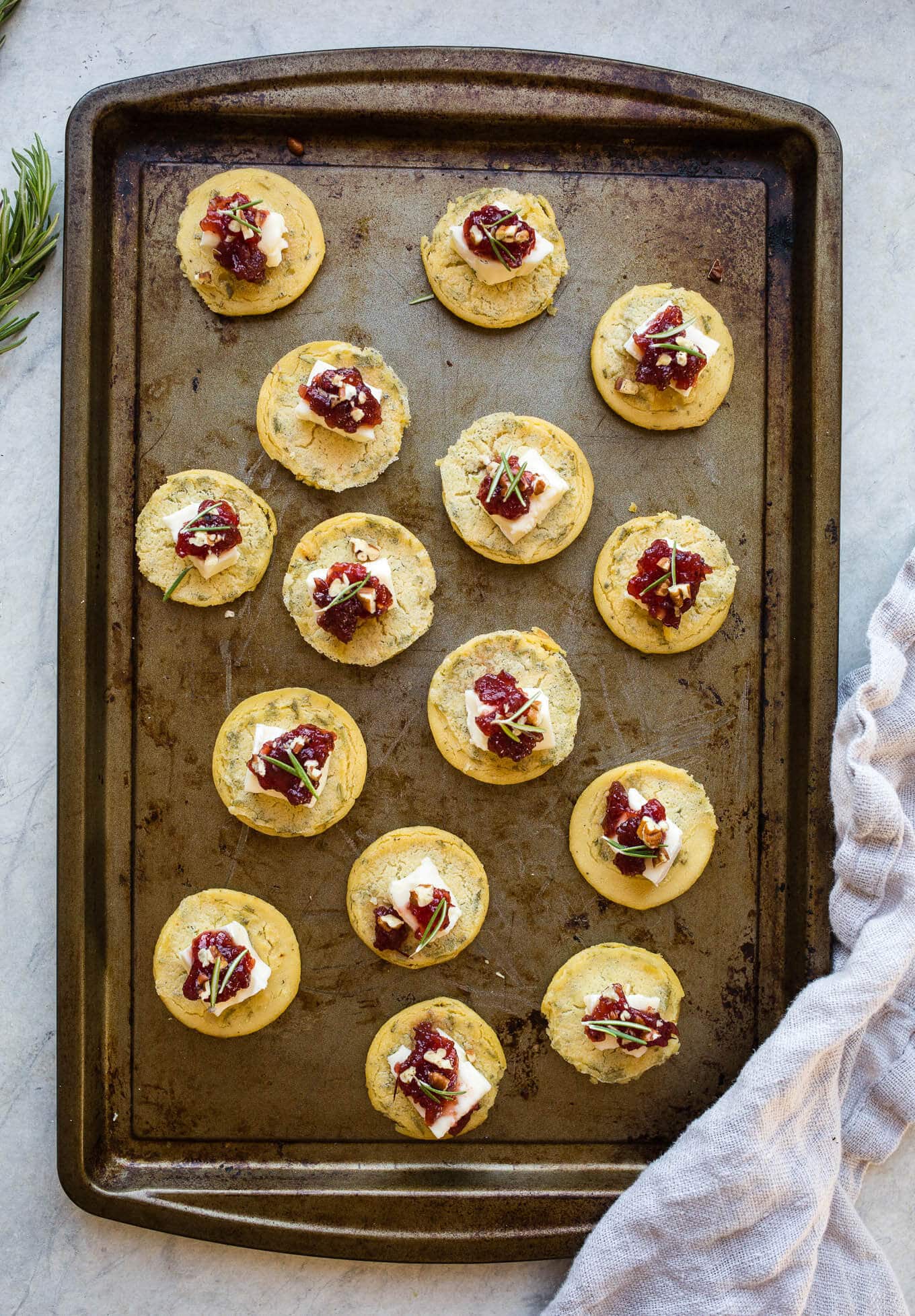 Socca Cranberry Brie Bites are an easy appetizer recipe made from naturally gluten-free chickpea flatbread, brie, cranberry relish, and chopped pecans. Gluten-free.