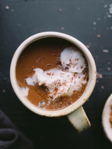 Hot chocolate in a mug topped with coconut cream and chocolate shavings.