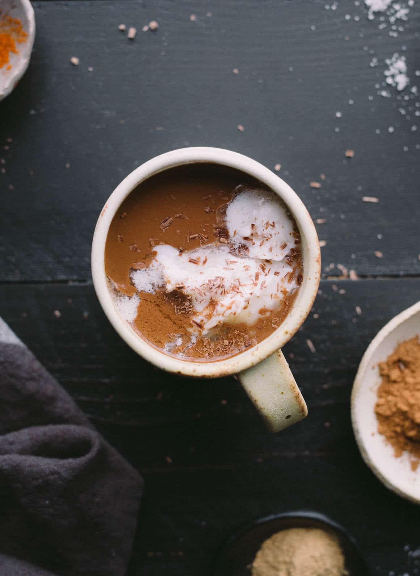 A mug of hot chocolate topped with coconut cream and chocolate shavings.