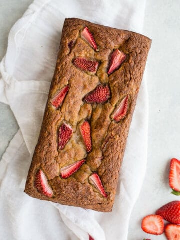 Roasted Strawberry Banana Bread made with almond flour, gluten-free oat flour, coconut sugar, ripe bananas, and topped with extra strawberries. A healthy banana bread recipe that is gluten-free, dairy-free, and refined sugar-free!
