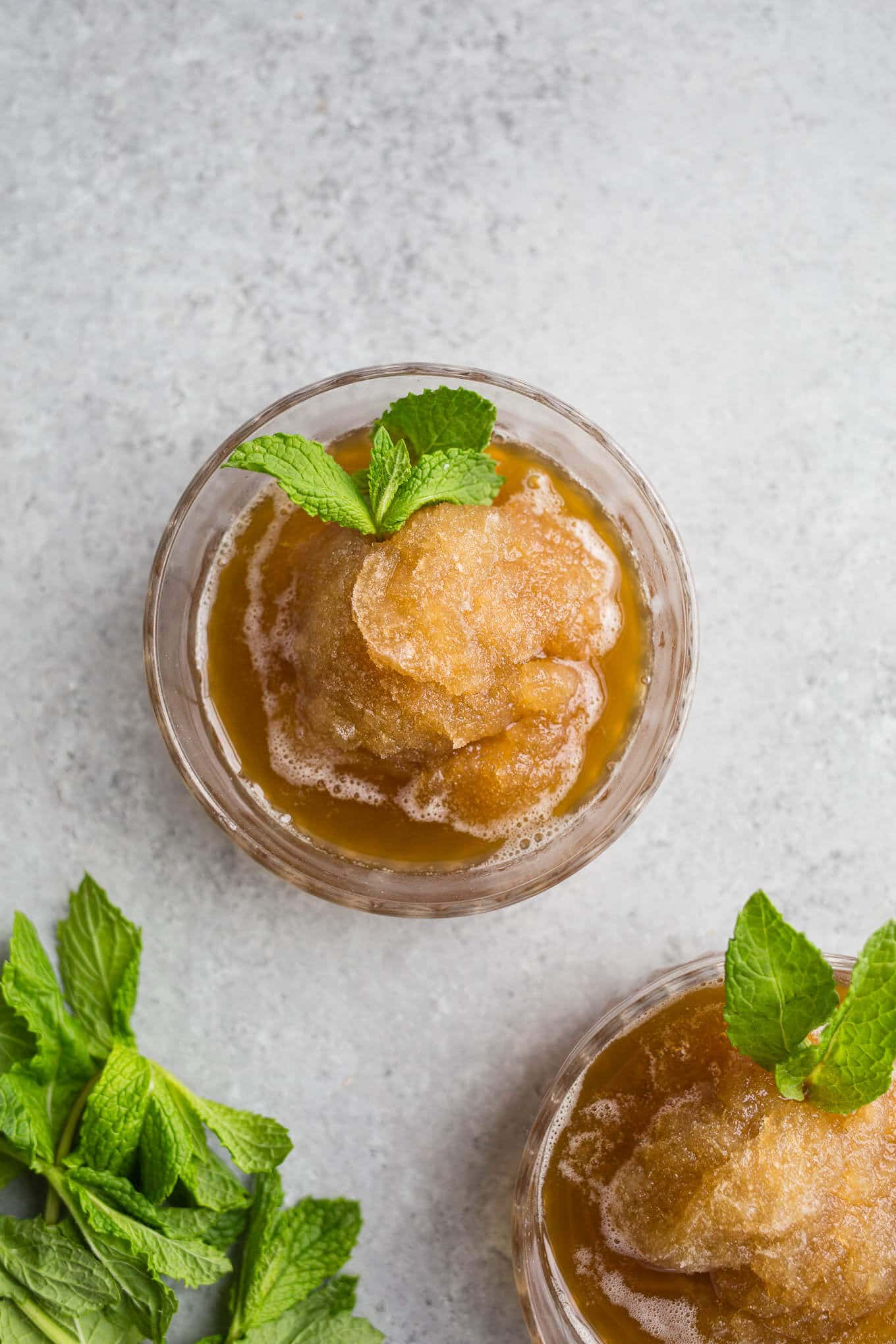 Mint Julep Granitas are made with a honey and mint infused simple syrup, bourbon, and are frozen until icy, flaked with a fork and frozen again. Served in a cup and garnished with mint.