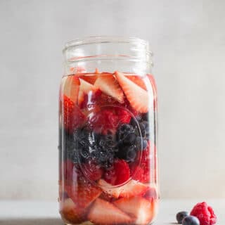 A large glass jar with berries.