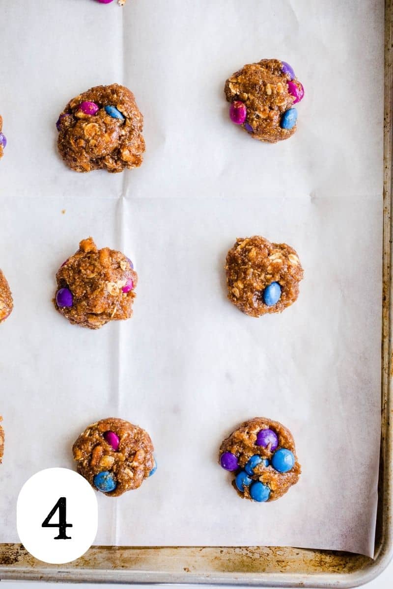 Cookie dough balls in even rows on a parchment lined baking sheet. 