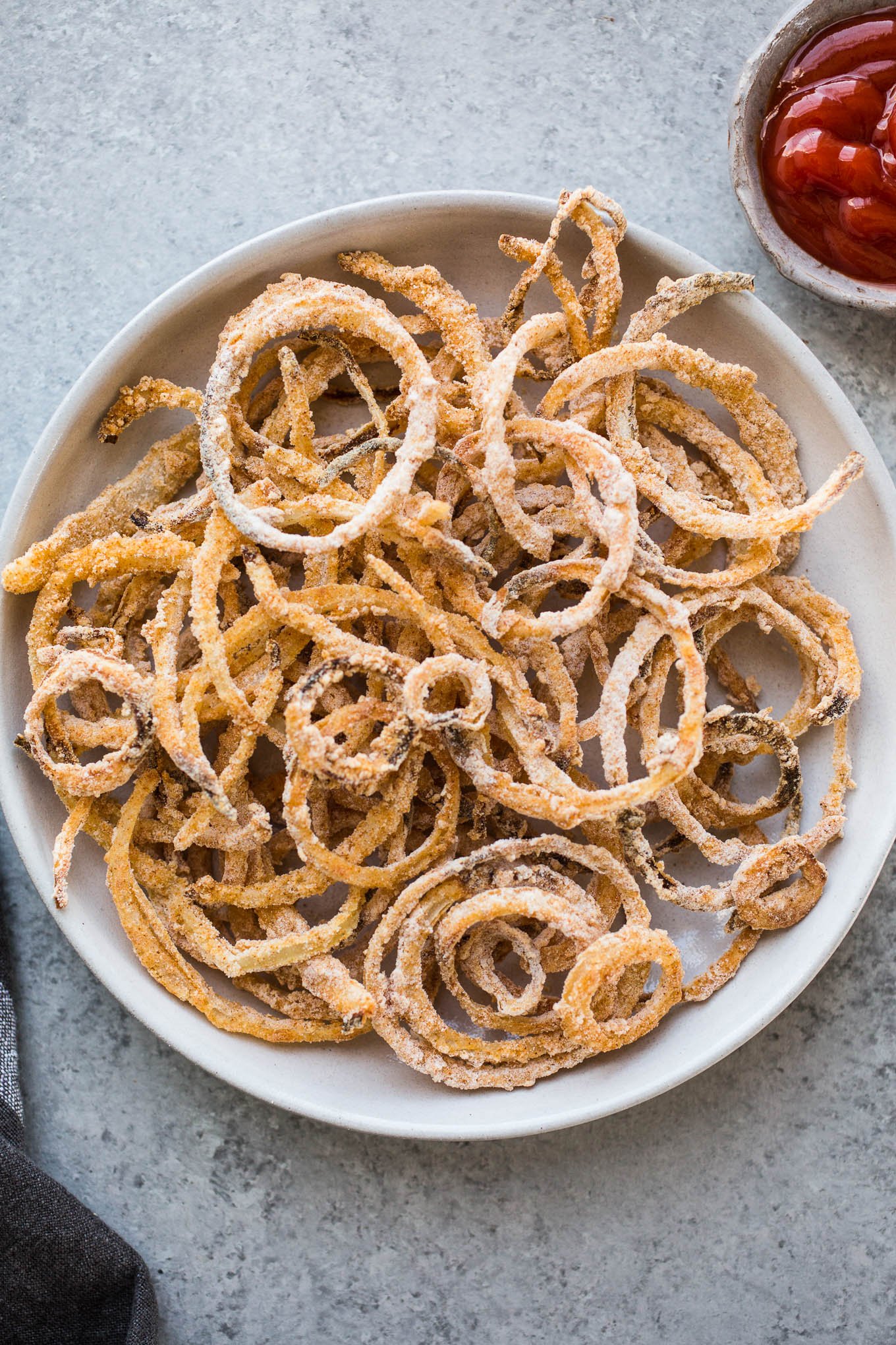 A Gluten-Free Onion Strings recipe that is baked, not fried. Made with white rice flour, dairy-free buttermilk, and spices, these won't last long! 