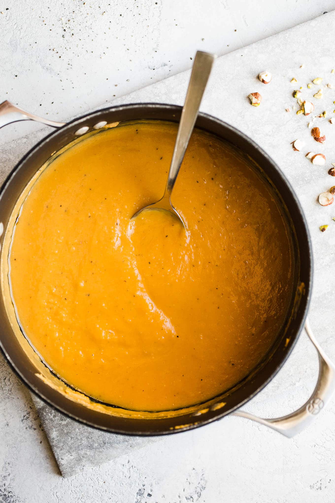 A large pot of sweet potato soup on a marble surface.