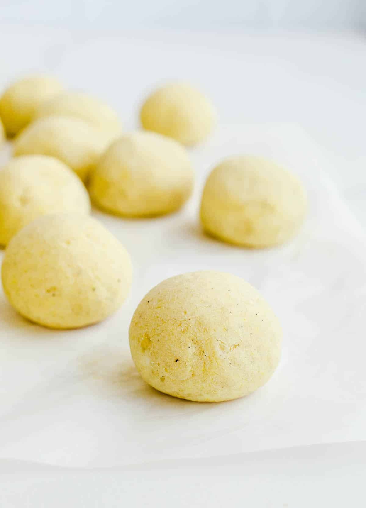 Baked bread balls on white parchment paper.