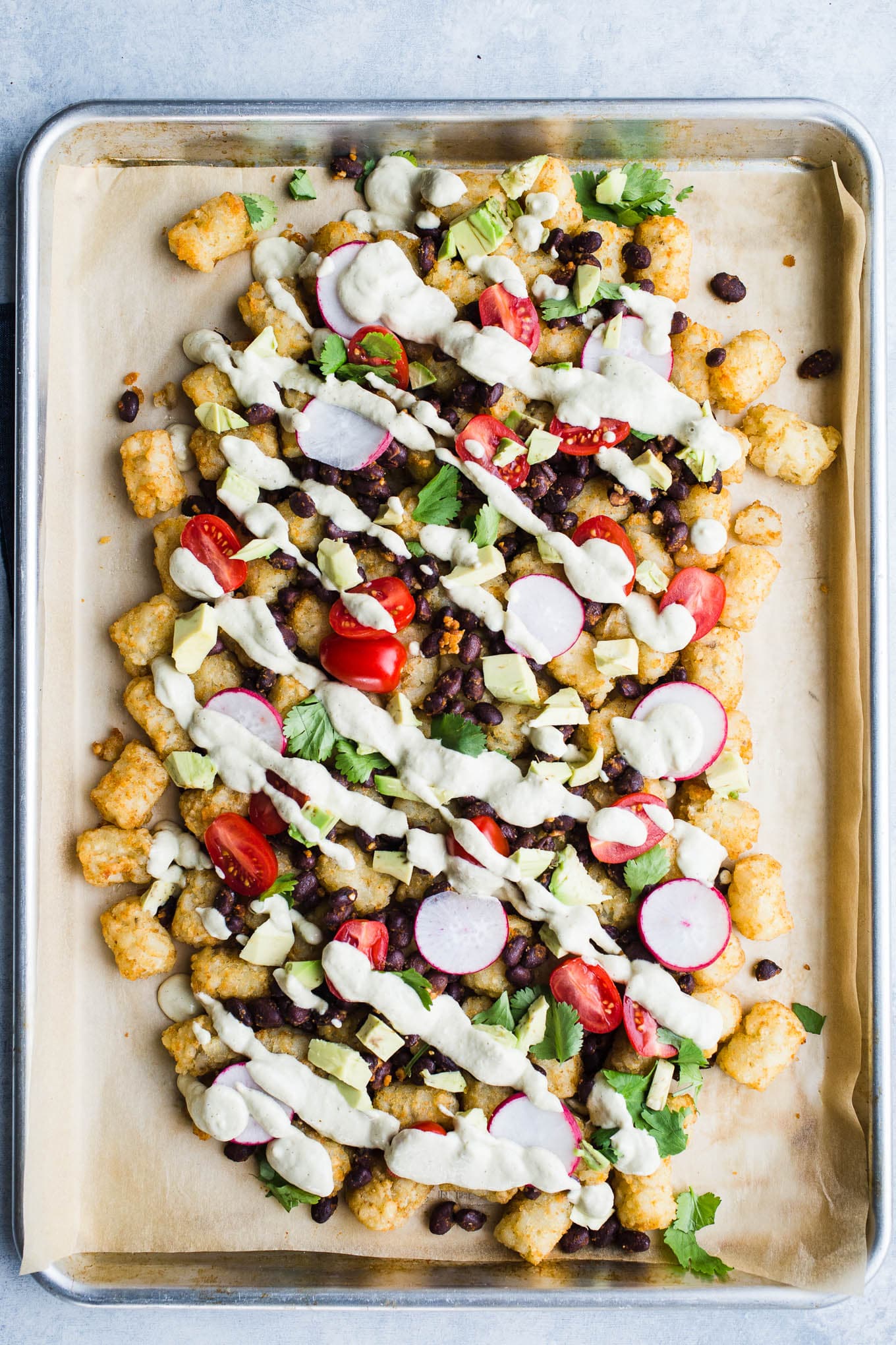 Vegan Salsa Verde Totchos made with a green salsa cashew cheese sauce and loaded with vegetarian toppings. A gluten-free tater tot nachos recipe!