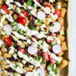 Tater tot nachos loaded with toppings on a pan.