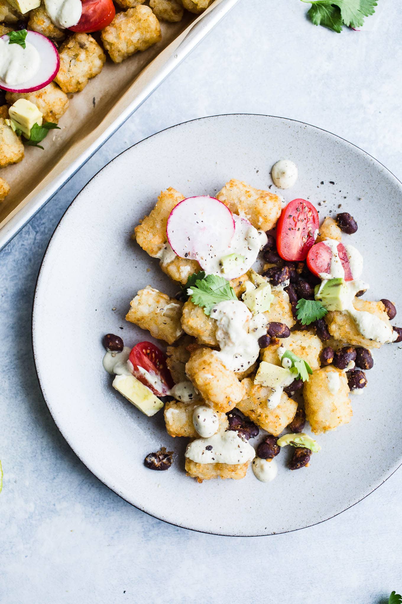 Vegan Salsa Verde Totchos made with a green salsa cashew cheese sauce and loaded with vegetarian toppings. A gluten-free tater tot nachos recipe!