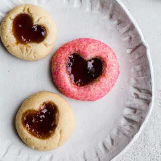 Heart thumbprint cookies on a white plate.