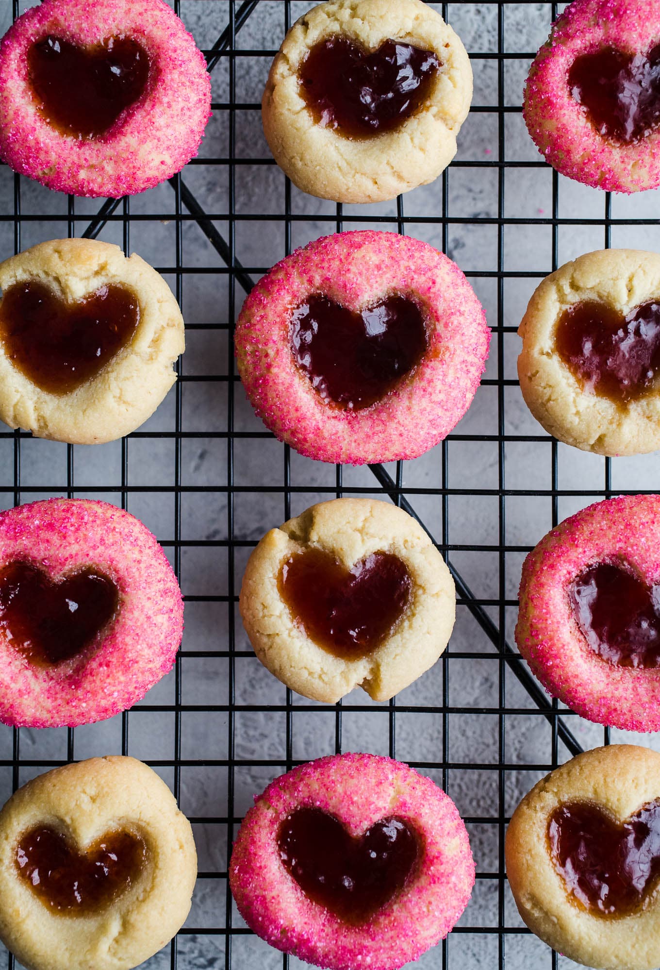 Baked heart cookies with jam on a cooling rack.