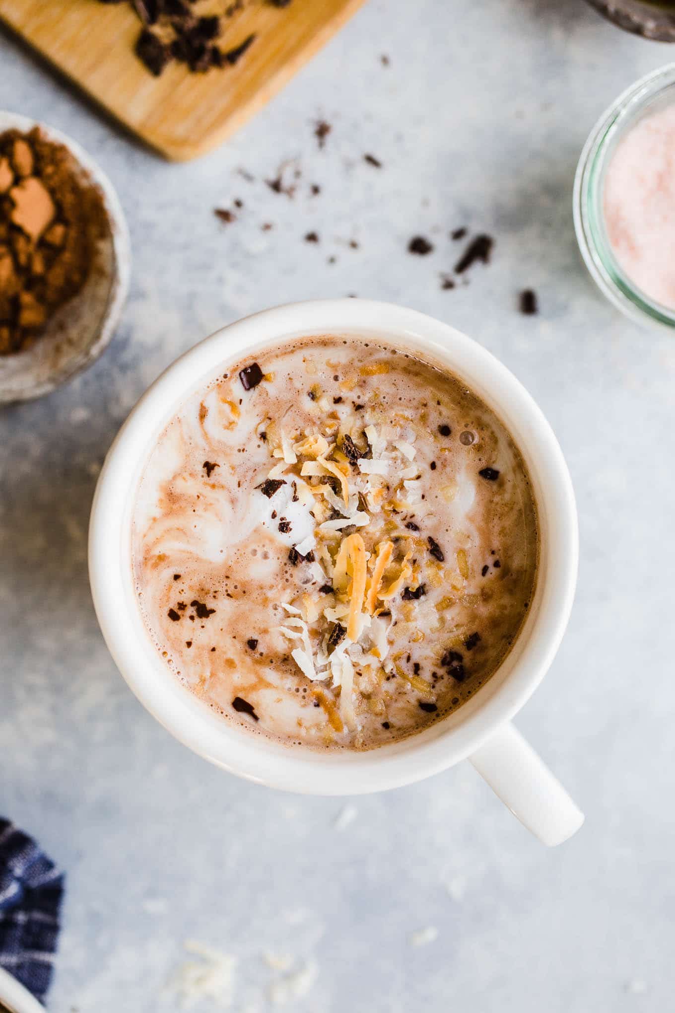 Toasted coconut hot chocolate topped with coconut whipped cream, chocolate shavings, and toasted coconut.