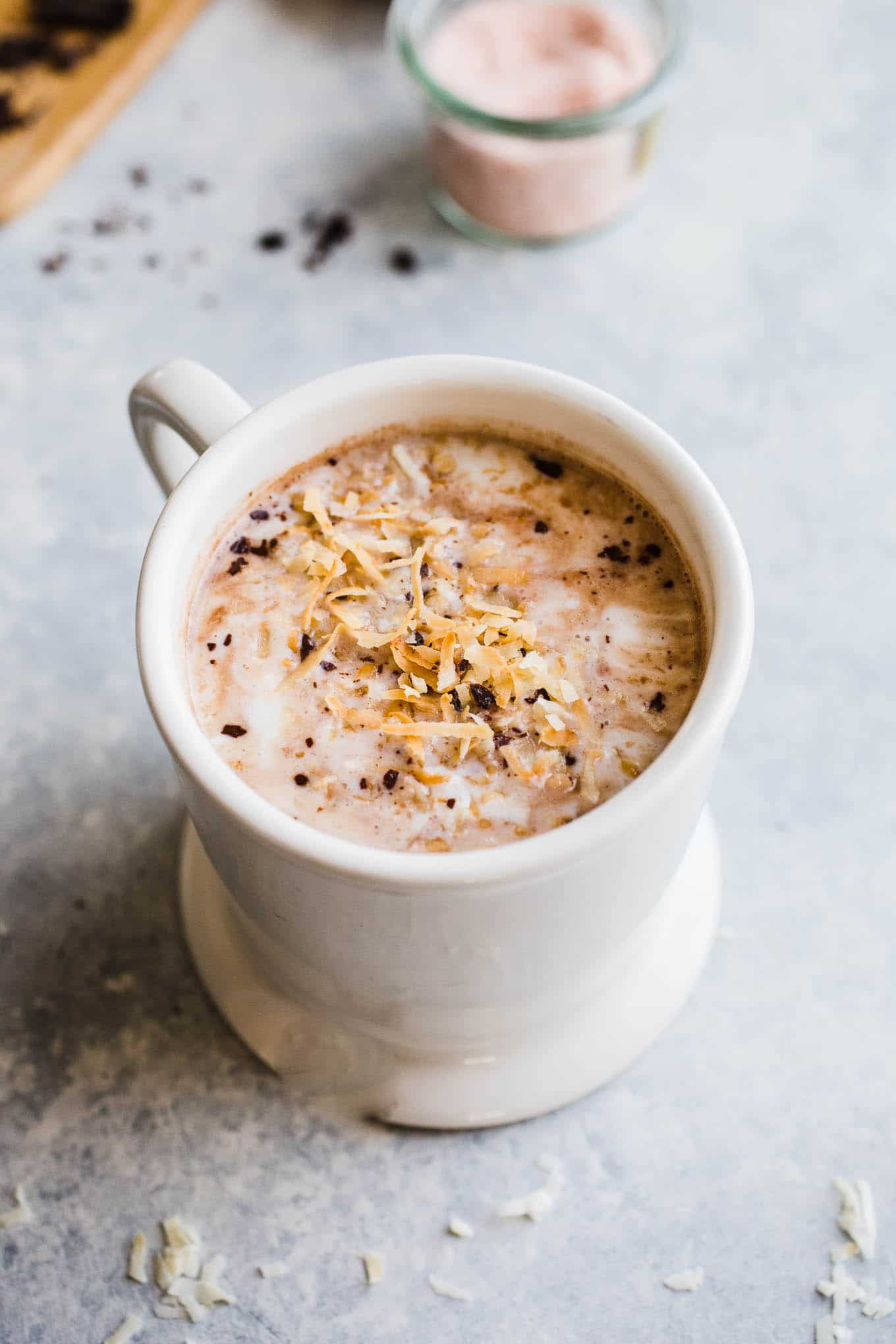 Toasted coconut hot chocolate topped with coconut whipped cream, chocolate shavings, and toasted coconut.