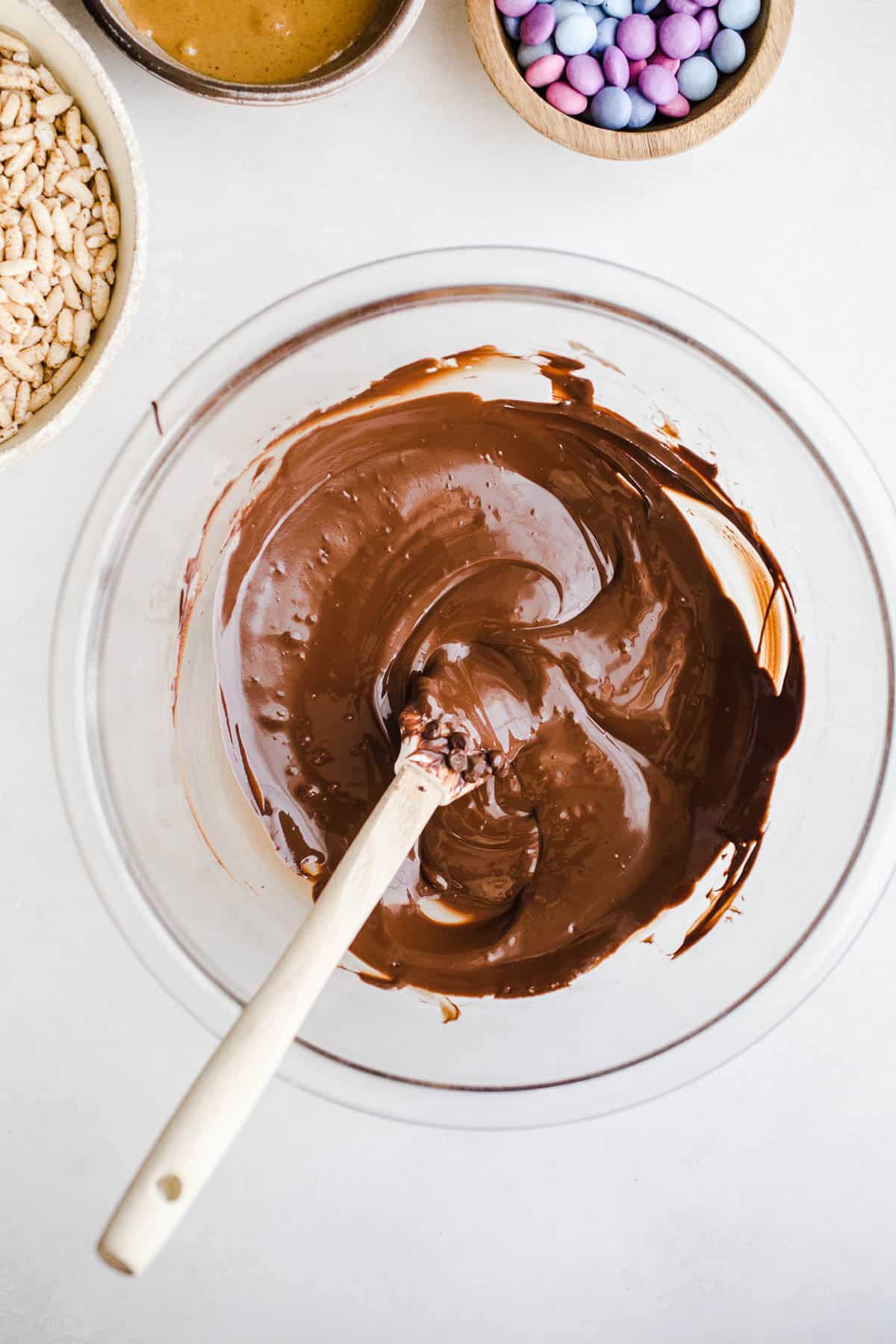 Melted chocolate in a glass bowl with a spatula.