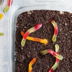 Dirt cake with gummy worms on top in a baking pan.