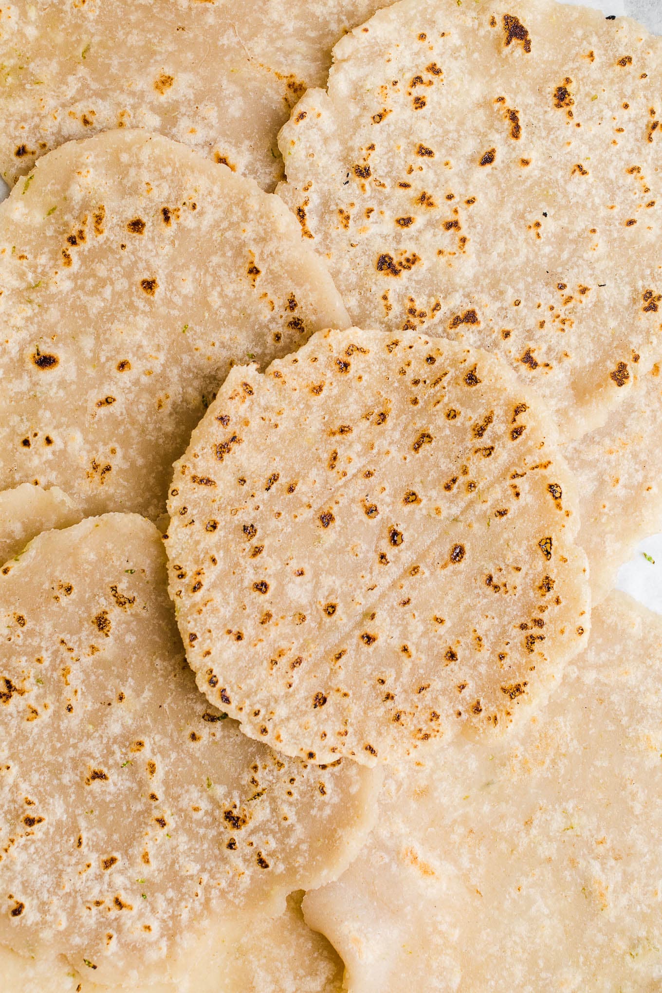 Brown rice tortillas layered across a piece of parchment paper.