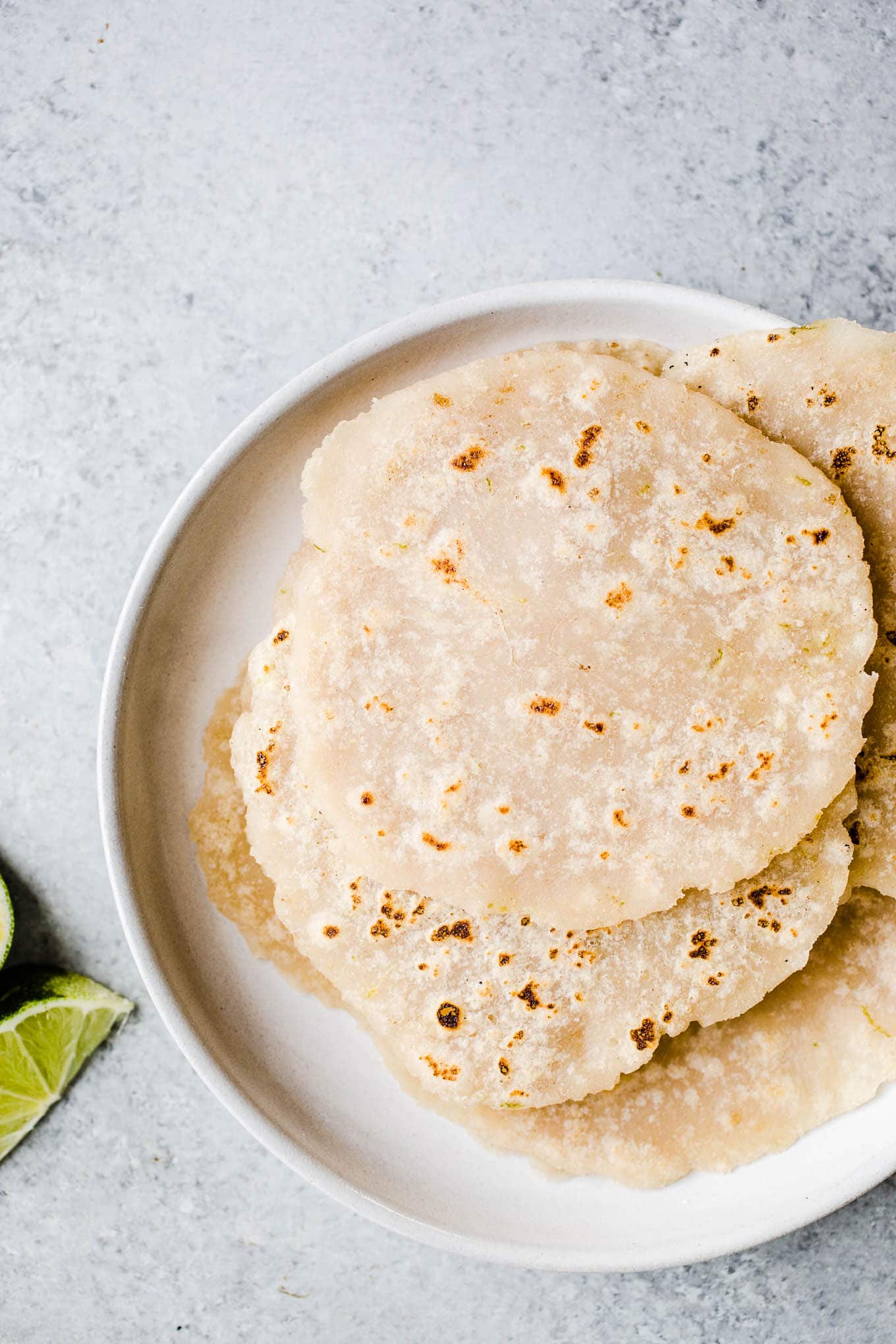 Fresh brown rice tortillas stacked on a white plate.