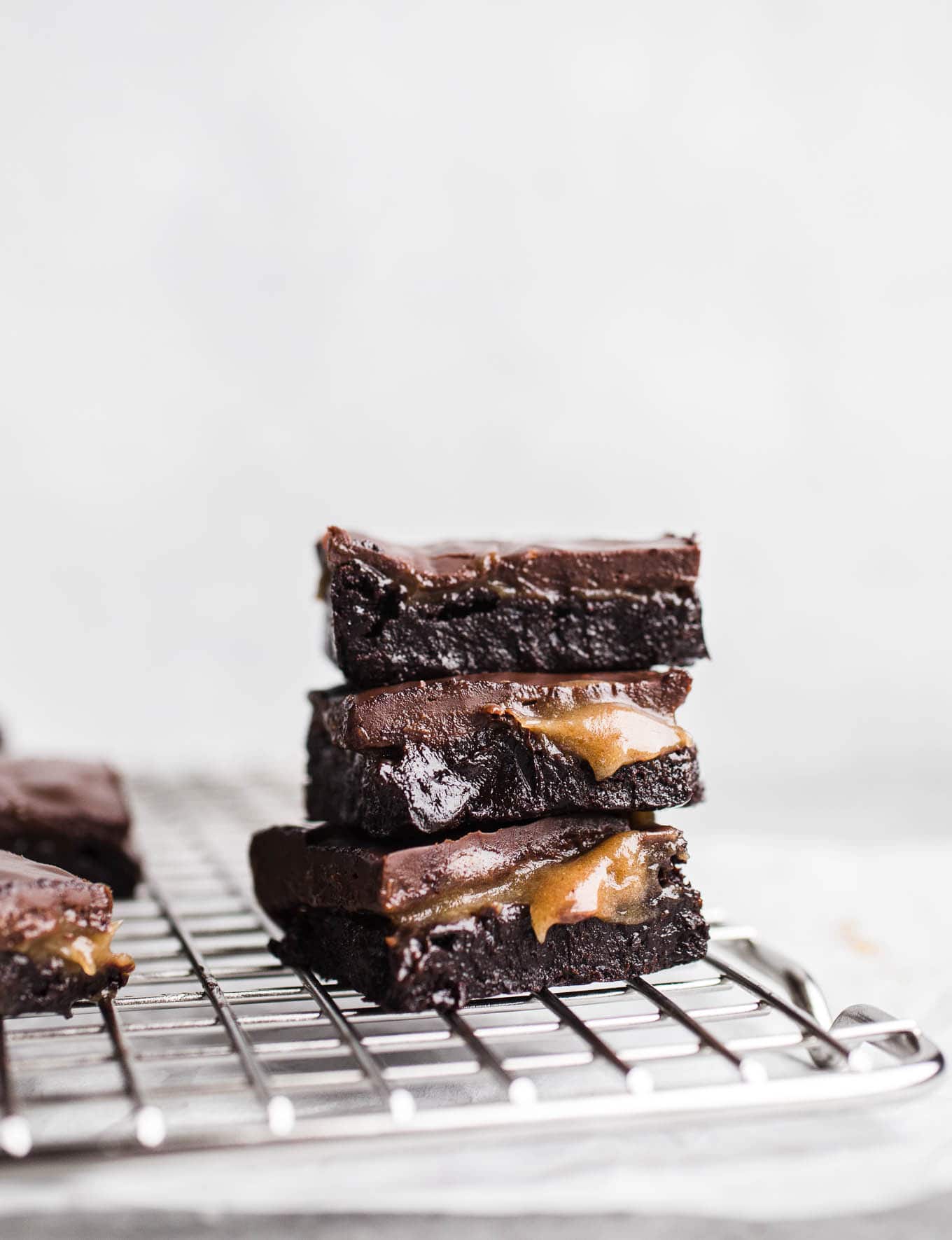 Caramel brownies stacked on a wire rack. 