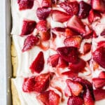 A three-layer sheet pan cake with coconut whipped cream and roasted strawberries on top.