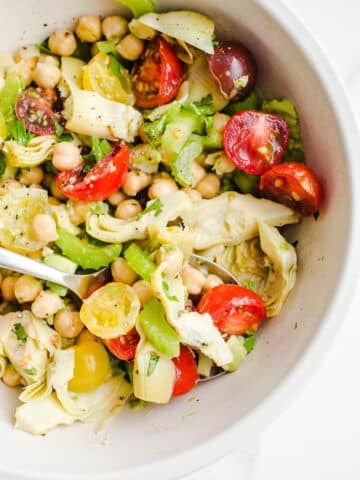 A salad with chickpeas, tomatoes, and avocado in a bowl.