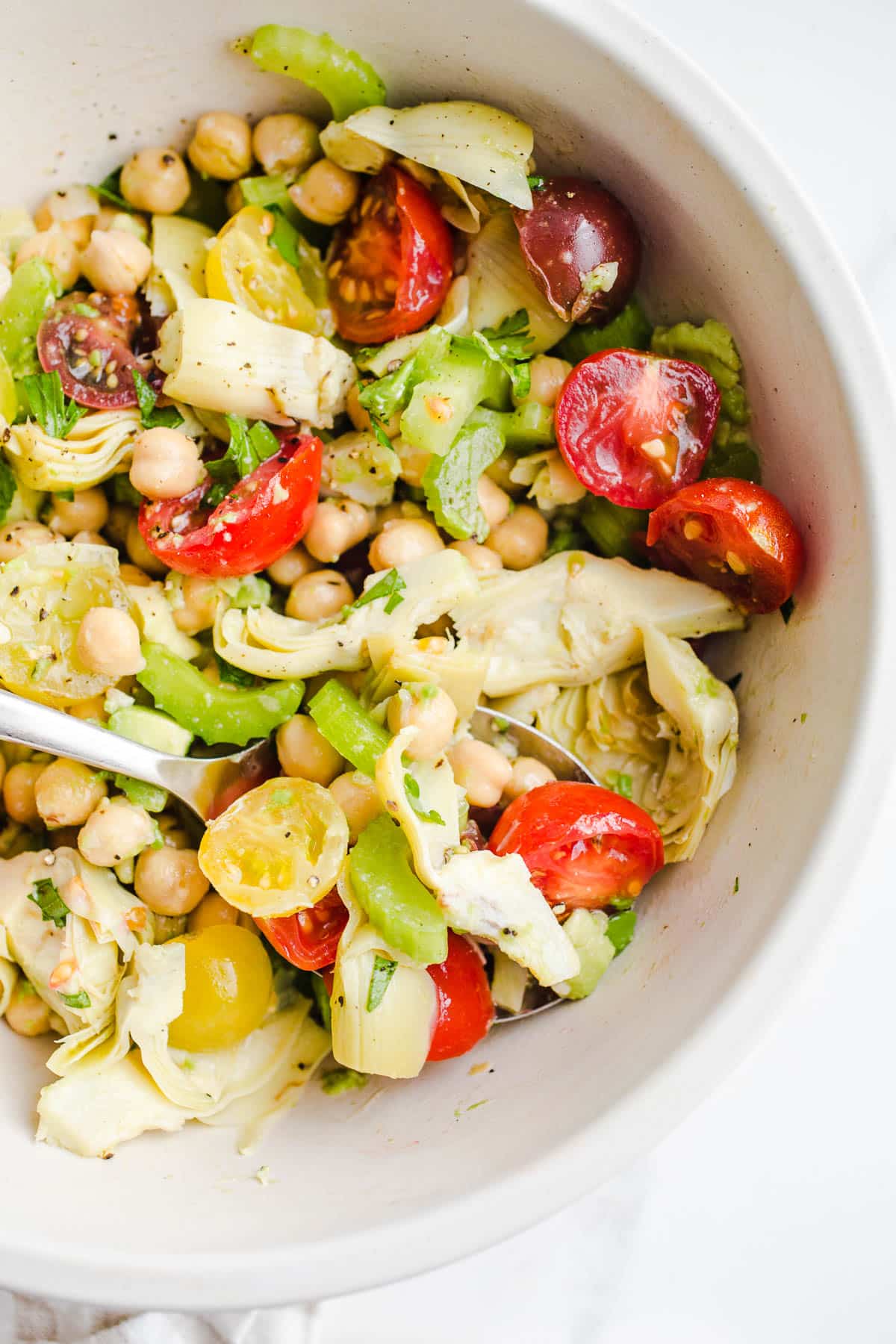 A salad with chickpeas, tomatoes, and artichokes in a bowl.
