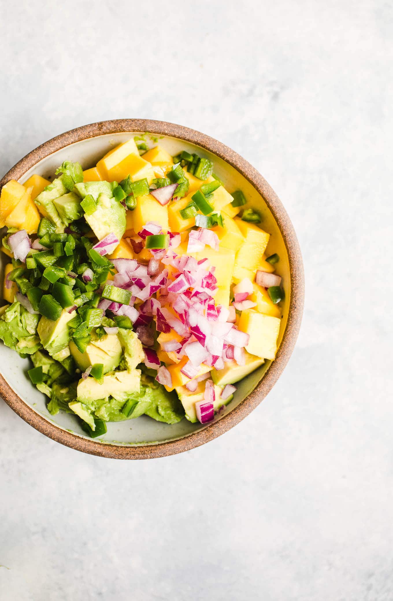 Mango, jalapeno, and red onion in a bowl.